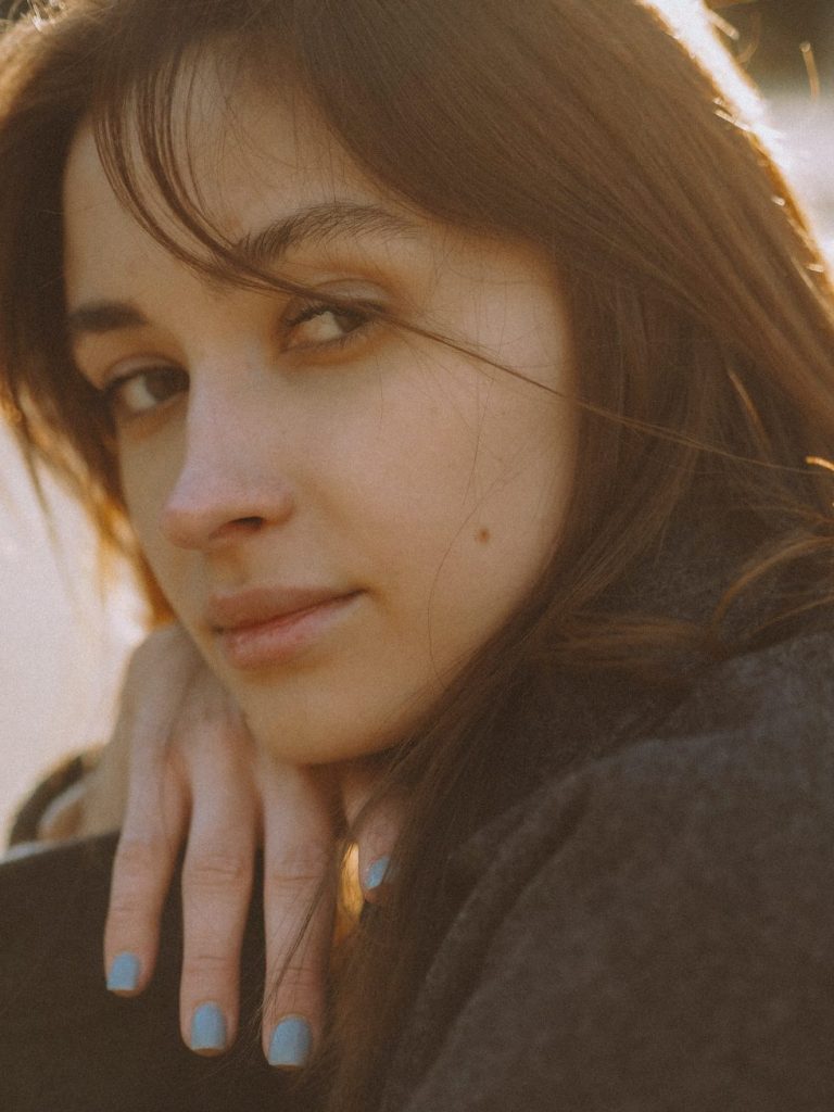 Young woman with soft lighting and blue nail polish
